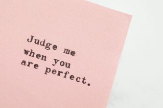 Close-up of an inspirational quote on pink paper, offering a message of judgment and perfection.